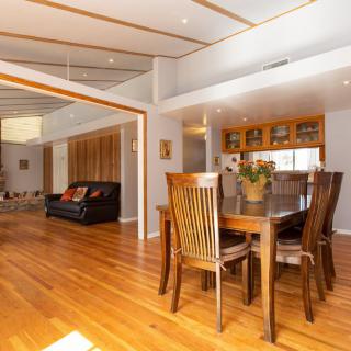 A spacious, modern interior featuring a dining table and chairs on polished wood flooring with an open view into the living area.