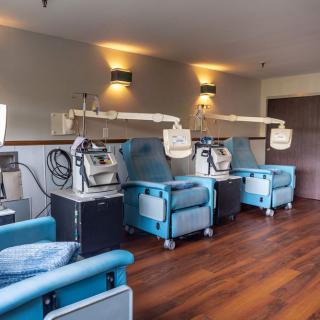 A modern treatment room with several dialysis chairs and medical equipment.