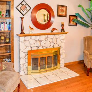 A cozy living room featuring a stone fireplace with decorative elements, a mirror, and comfortable seating.