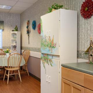 A cozy kitchen and dining area with a table, chairs, and decorated refrigerator.