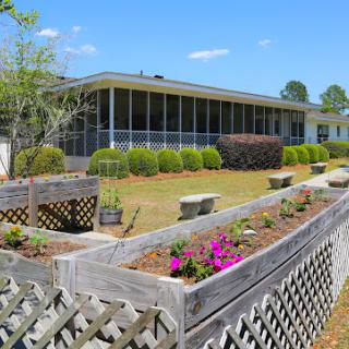 A serene garden view featuring vibrant flowers and a well-maintained house in the background.