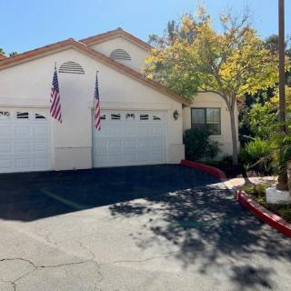 A sunny day view of a house with two garages and American flags displayed.