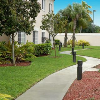 A landscaped garden with a winding pathway, surrounded by trees and bushes.
