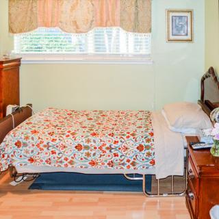 A cozy bedroom with a floral-patterned bedspread and classic wooden furniture.