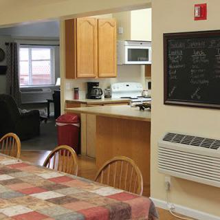 A cozy kitchen and dining area with a table surrounded by wooden chairs, featuring a chalkboard and modern appliances.