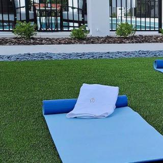 An outdoor setup with a blue yoga mat and towel on a grassy surface.