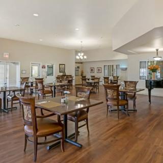 A spacious dining area with tables and chairs, featuring hardwood floors and elegant lighting.