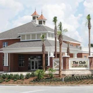 A clubhouse with brick architecture, surrounded by palm trees and landscaping.
