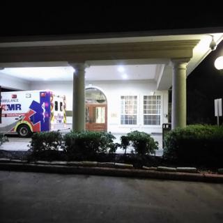 An ambulance parked outside a healthcare facility at night, illuminated by outdoor lights.