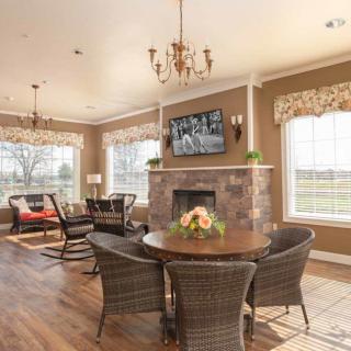 A cozy living room with a fireplace, television, and wicker chairs arranged around a wooden table.
