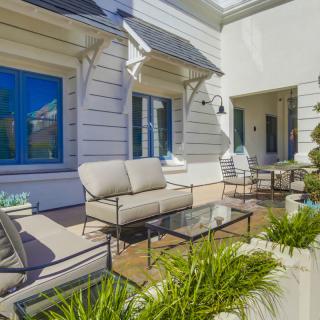 A modern patio with comfortable outdoor furniture and greenery under a sunny sky.