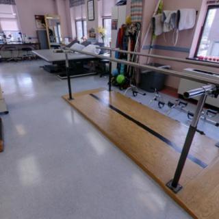 A physical therapy room equipped with parallel bars for rehabilitation exercises.