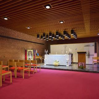 A serene interior view of a modern church chapel featuring an altar and seating.