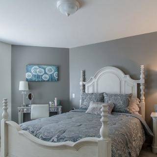 A stylish bedroom with gray walls, featuring a cozy bed and elegant decor.