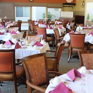 An elegantly set dining area in a restaurant with neatly arranged tables and chairs.