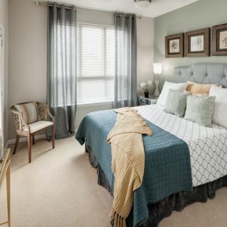 A cozy and modern bedroom with a neatly made bed, decorative pillows, and soft lighting.