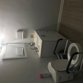 An accessible bathroom equipped with a toilet, sink, and handrails.