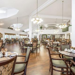 A spacious and elegantly designed restaurant dining area with wooden floors and chandeliers.