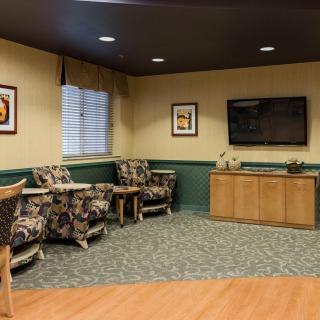 A cozy waiting room with patterned chairs, a mounted television, and decorative wall art.