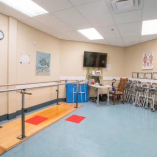 A physical therapy room equipped with parallel bars and various rehabilitation tools.