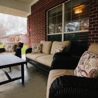 A cozy outdoor patio with comfortable seating and a table set against a brick wall.