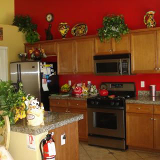 A modern kitchen with red walls, featuring wooden cabinets and stainless steel appliances.
