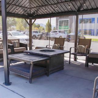 An outdoor seating area under a gazebo featuring a fire pit and comfortable chairs.