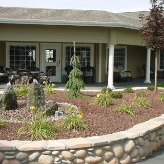 A beautifully landscaped patio area with shrubs and stone edging.