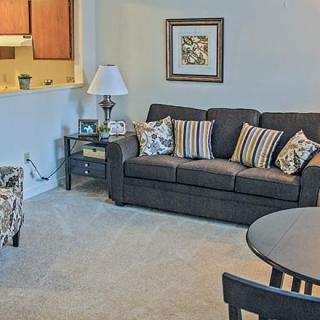A cozy living room with a dark sofa, decorative pillows, and a stylish lamp beside a coffee table.
