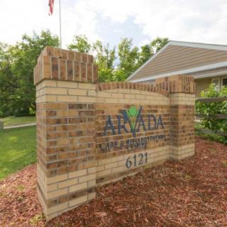 A brick entrance sign for Arvada Estates, surrounded by landscaping and trees.