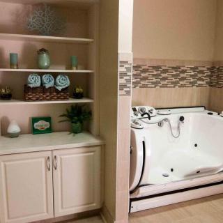 A bathroom with a built-in bathtub and neatly organized shelves with towels and decor.