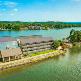 Aerial view of a waterfront building surrounded by a picturesque lake and lush green trees.