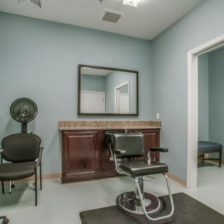 A modern salon interior with a barber chair, mirror, and hairdryer.