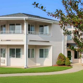 A modern residential building with a well-maintained lawn and surrounding greenery.