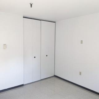 A minimalist empty room with white walls and a closed closet.