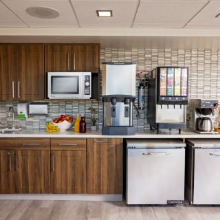 An office kitchen area with various appliances including a microwave, coffee maker, and drink dispenser.