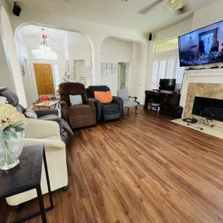 A cozy living room with hardwood floors, featuring a fireplace and a mounted TV.