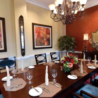 An elegantly decorated dining room with a set table and a chandelier overhead.