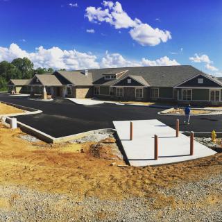 A newly constructed building with a freshly paved parking lot under a clear blue sky.
