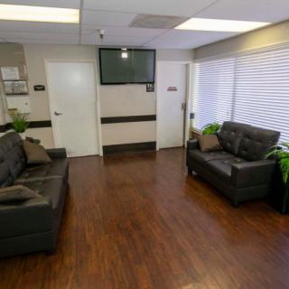 A modern waiting room with leather sofas, a television, and hardwood floors.