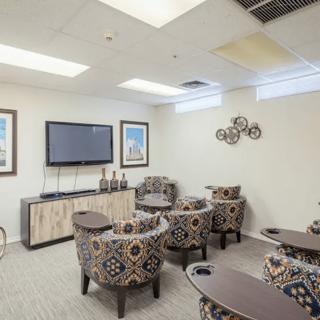 A cozy lounge area with decorative chairs and a large television, featuring artwork on the walls.