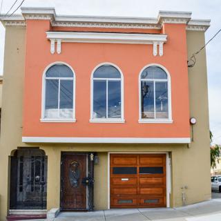 A two-story house with an orange facade and arched windows.