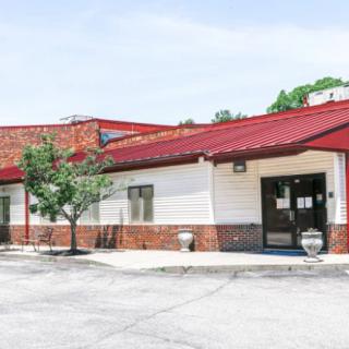 A small restaurant with a red roof and adjacent parking lot.