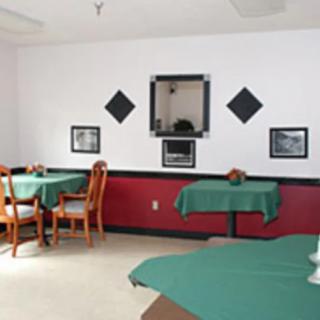 A small dining area with tables covered in green tablecloths and simple decor.
