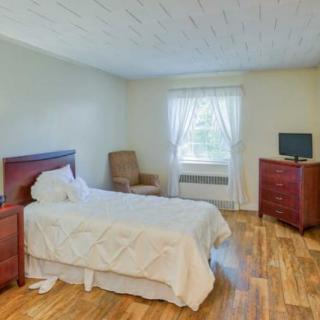 A simple bedroom with a single bed, dresser, chair, and television.