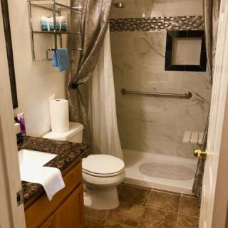 A modern bathroom with a shower, toilet, and sink.