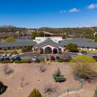 Aerial view of a large building with surrounding landscape and parking lot.