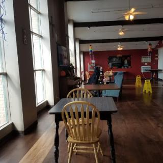A cozy cafe interior featuring wooden furniture and large windows, inviting a relaxed ambiance.