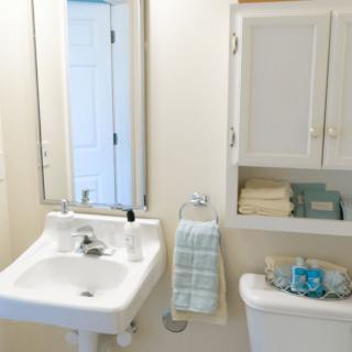 A clean and organized bathroom with a sink, mirror, and cabinet.