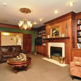A cozy living room with a fireplace, wood paneling, and elegant decor.